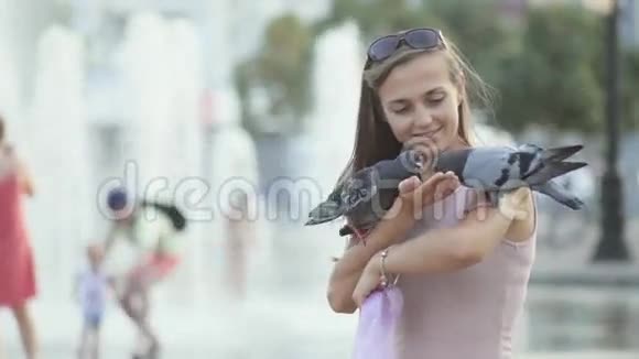 有魅力的年轻女子在公园里喂鸽子视频的预览图