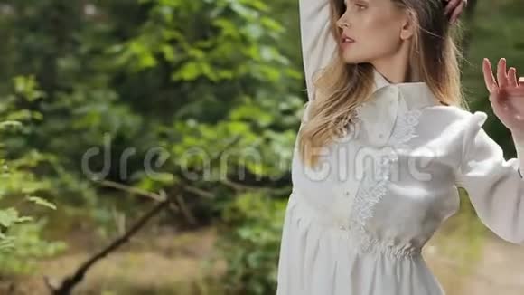 绿色森林里一个穿着白色裙子的漂亮女孩在镜头前摆姿势视频的预览图