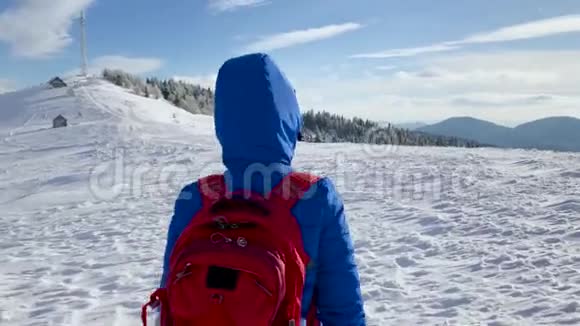 孤独的旅游女孩沿着白雪覆盖的山顶散步晴朗的霜冻天气视频的预览图