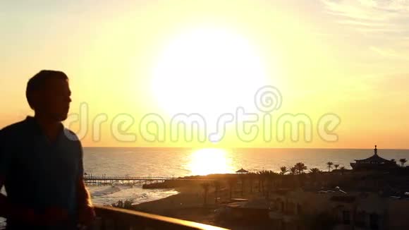 黎明时分阳台上有海景的男人戴着太阳镜视频的预览图