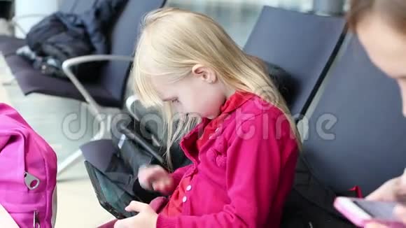 女儿和母亲正在平板电脑和手机上打字等待飞机视频的预览图