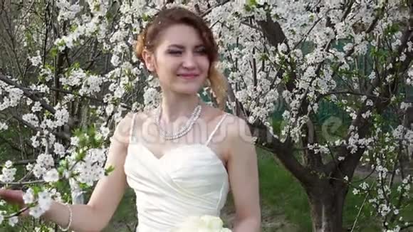 新娘站在美丽的春天花园里视频的预览图