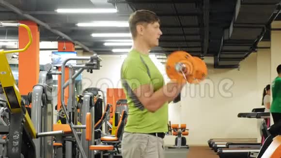 一个超重的人站在健身房时举起一个ez杠铃锻炼肱二头肌健身健康的生活方式视频的预览图