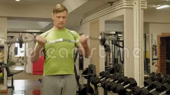 一个超重的人站在健身房时举起一个ez杠铃锻炼肱二头肌健身健康的生活方式视频的预览图