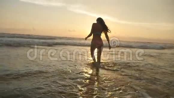 美丽的女孩长发在日出时摆在海边穿比基尼的漂亮年轻女子站着视频的预览图