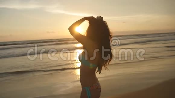 美丽的年轻女子穿着比基尼站在夕阳下的海里在海滩上享受假期生活的女性视频的预览图