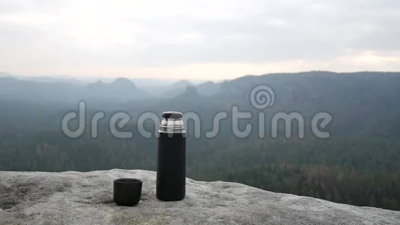在岩石上使用旅行热水瓶带茶的吸烟杯真空瓶视频的预览图