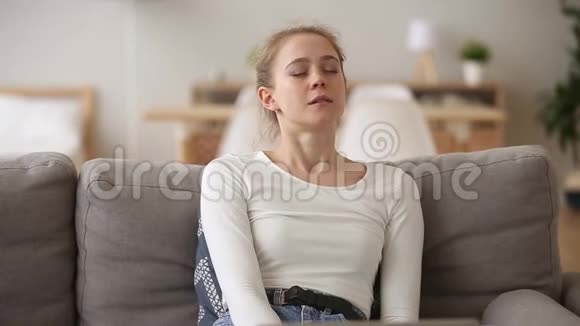 冷静的女人坐在沙发上呼吸家里的新鲜空气视频的预览图