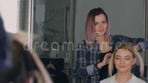 在一家美容院古怪的造型师为女孩们做专业的造型金发碧眼的发型视频的预览图