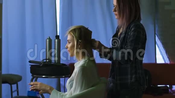 在一家美容院古怪的造型师为女孩们做专业的造型金发碧眼的发型视频的预览图