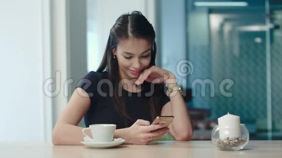 美丽的女孩在咖啡馆里喝咖啡用电话视频的预览图