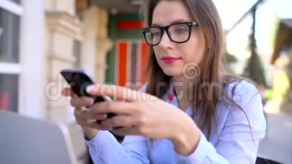 一位在户外咖啡馆里用智能手机的美女视频的预览图