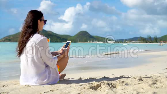 带智能手机的年轻女性在热带海滩度假加勒比海上有手机的海滩美女视频的预览图