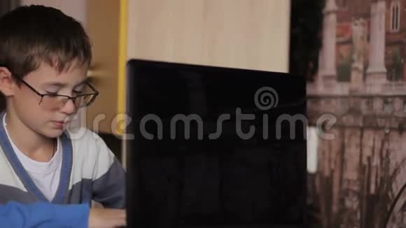 带着眼镜的男孩在家里玩电脑视频的预览图