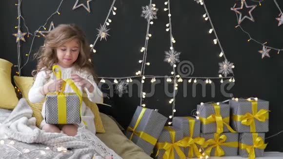 女孩在花环的背景下展开圣诞礼物视频的预览图