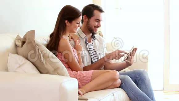 一对在沙发上使用平板电脑的可爱夫妇视频的预览图
