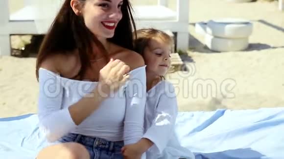 精致的女孩和她的小女儿在海滩上的平房里放松和玩耍视频的预览图