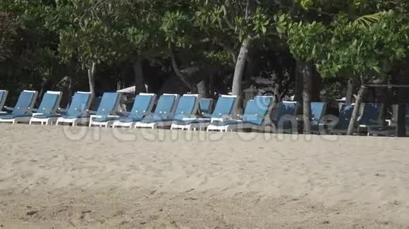 温暖的海浪在热带度假胜地的沙滩上带着雨伞和躺椅视频的预览图