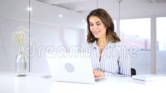 坐在办公室上班的妇女在笔记本电脑上的视频聊天视频的预览图