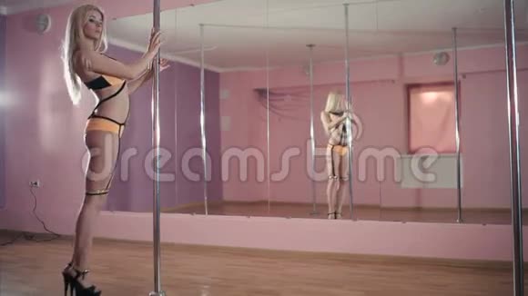 美丽的金发女郎在舞蹈室的杆子上跳舞视频的预览图