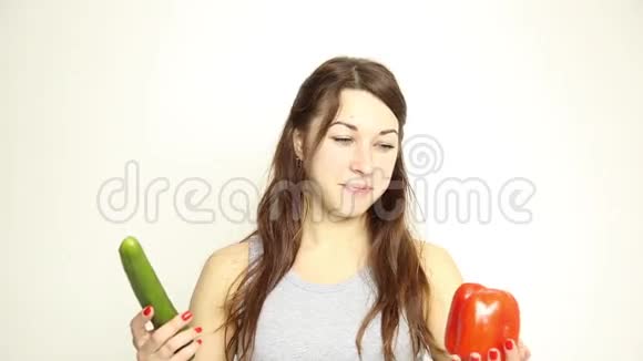 美丽的年轻女人吃蔬菜拿着黄瓜和红胡椒健康食物健康身体概念视频的预览图
