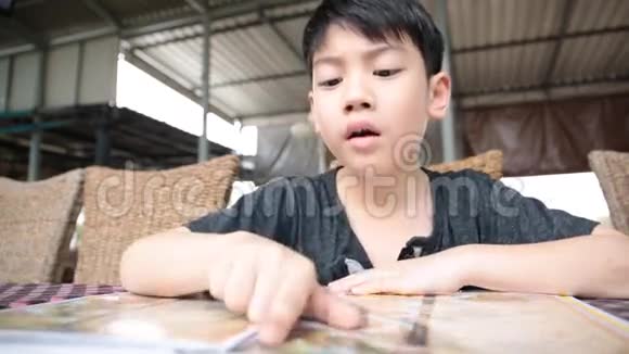 亚洲可爱男孩阅读菜单书和点视频的预览图