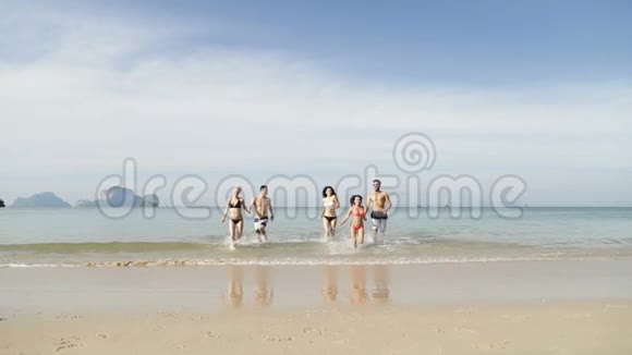 人们从沙滩上的水中奔跑青年男女群体快乐游客视频的预览图