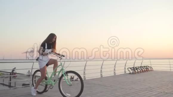 日出或日落时年轻迷人的女士骑着老式自行车在海边视频的预览图