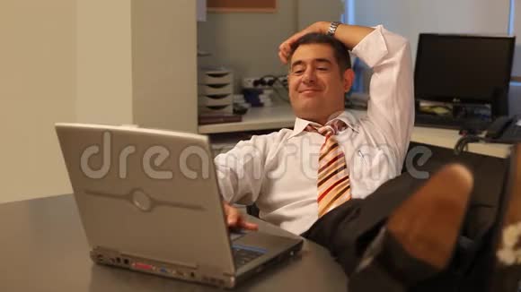 放松的商人在办公室里用笔记本电脑视频的预览图