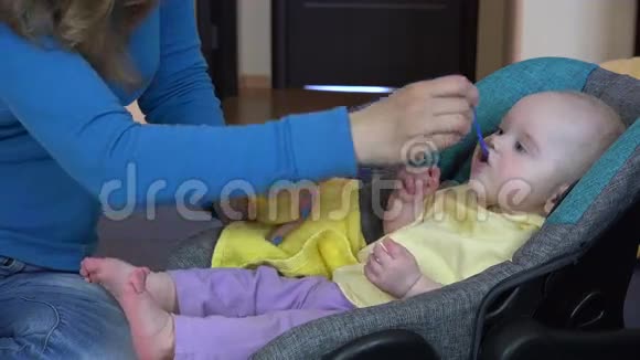 女人用勺子喂饥饿的婴儿玉米泥4K视频的预览图