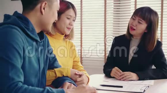 性格开朗的年轻人和妻子一起坐在办公桌前签署一些文件购买新房房产视频的预览图