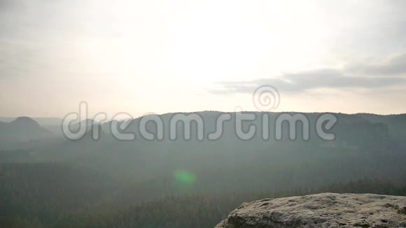 摄影师穿着黄色黑色温暖的衣服站在岩石的视点上拍摄朦胧的早晨景观在岩石里远足视频的预览图