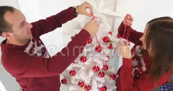圣诞快乐的一对夫妇装饰着白色的基督弥撒树视频的预览图