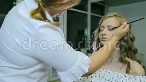 专业化妆师将色调粉涂在金发模特眼皮上做眼影视频的预览图