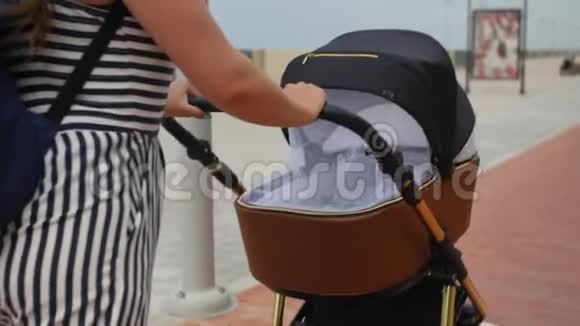 现代母亲带着婴儿车在长廊散步家庭母性和人的概念有婴儿的幸福母亲视频的预览图