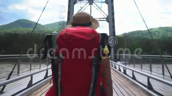 那个带着红色背包的旅行者的女人沿着斜拉桥穿过山河视频的预览图