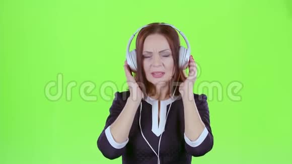 女人在耳机上听音乐绿色屏幕视频的预览图