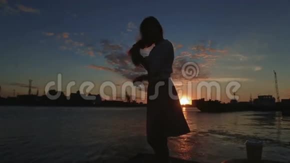 女人在夕阳河港梳头跳舞视频的预览图