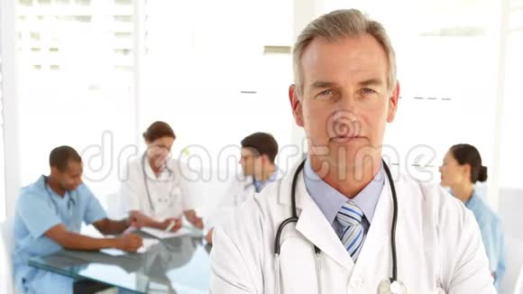 医生看着摄像机和他身后的工作人员视频的预览图