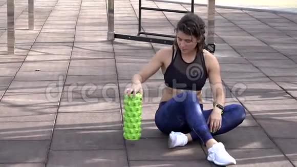 主题运动与康复运动医学美丽强壮苗条的白种人女子运动员坐在泡沫滚筒绿田旁视频的预览图