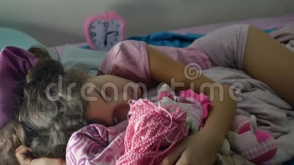 可爱的小女孩晚上睡在沙发床上拥抱她的娃娃在室内女孩深肤色的少年可爱的睡着了视频的预览图