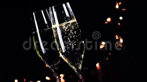 在黑色暗光背景下两瓶带有金色气泡的香槟酒杯新年气氛视频的预览图