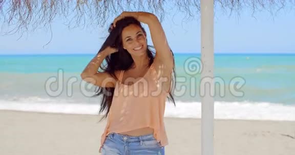 海滩伞下快乐美丽的年轻女子视频的预览图
