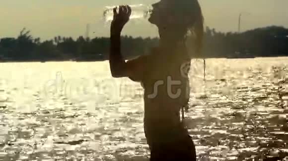 女人在日落时分喝水走出大海视频的预览图