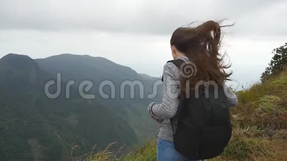 年轻的女徒步旅行者背包伸向山顶举起双手女游客站在视频的预览图