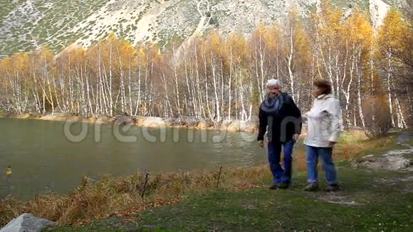 幸福的老夫妇沿着湖岸散步微笑着视频的预览图