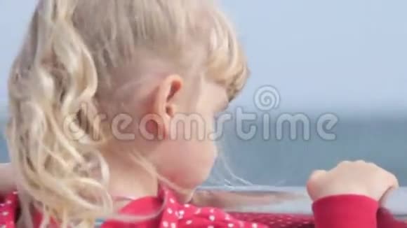 年轻的金发女孩看着海滩上的大海微笑着回首往事视频的预览图