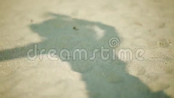 沙滩上女人的影子她在沙滩上走来走去玩帽子视频的预览图