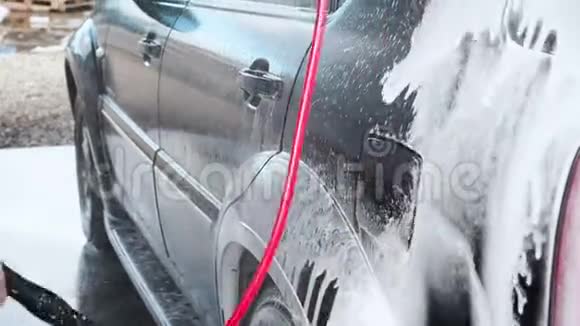 汽车自动洗车过程高压清洗汽车泡沫的喷水器侧面视频的预览图