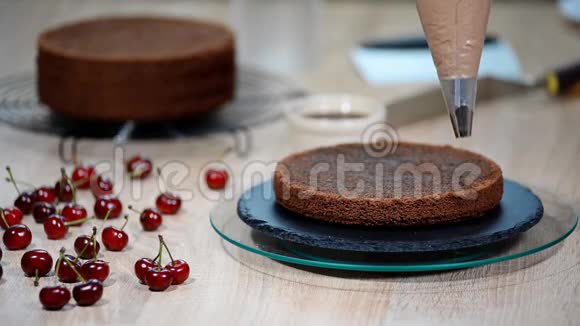 女性糕点厨师在厨房的开胃层蛋糕上挤压巧克力奶油视频的预览图